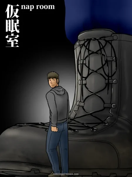 Man in gray hoodie and blue jeans stands beside giant black boot, hand on crotch, for boot fetish sex